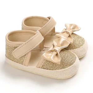 Side detail view of gold glitter baby walker shoes with patent leather bows