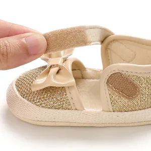Detailed view showing the adjustable velcro strap on a gold glitter soft-sole baby walking shoe