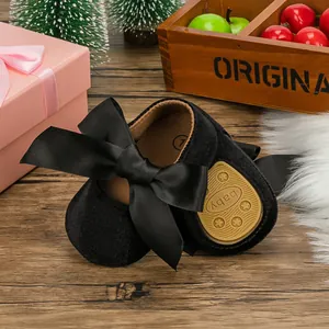 Close-up of black velvet baby princess shoes with a large satin ribbon bow