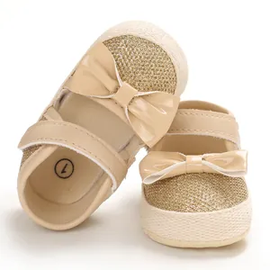 Close-up detail of gold glitter baby princess walking shoes with bow and soft sole