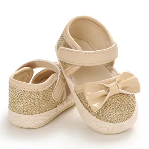 Detail shot of sparkling gold baby princess shoes with soft soles and decorative bow