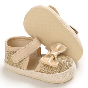 Detailed view of baby princess pre-walker shoes with gold glitter texture and beige bow