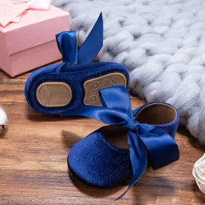 Close-up of blue velvet baby girl shoes with elegant satin bows and soft anti-slip soles.