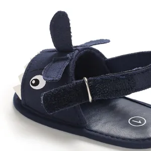 Close-up detail of navy blue cartoon shark baby sandals with soft sole and strap.