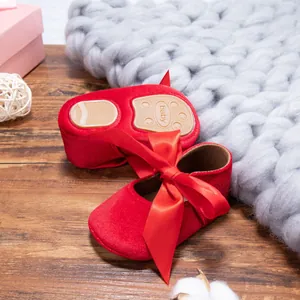 Detailed view of red velvet baby princess shoes with soft soles and a large silk bow