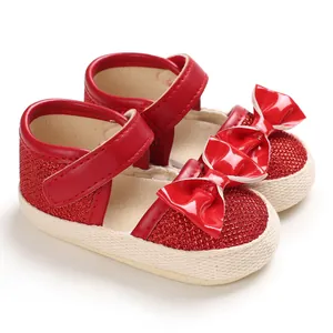 Close-up of red glittery baby princess shoes with patent leather bow detail.