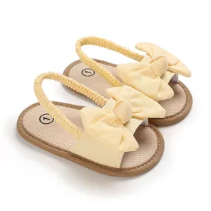 Detalle de sandalias amarillas de bebé con lazos decorativos y tira elástica al talón