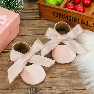 Detailed close-up of pink velvet infant princess shoes featuring large ribbon bows.