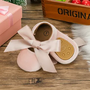 Close-up detail of pink velvet baby princess shoes with a large silk ribbon bow