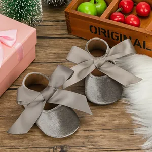 Detailed view of grey velvet baby princess shoes featuring elegant silk ribbon bows on wood