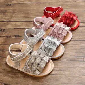 Detailanzeige glitzernder Babysandalen in Rot, Rosa, Silber und Gold auf Holzgrundlage.