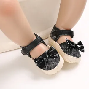 Detailed macro view of baby princess walking shoes with black bow and soft soles.
