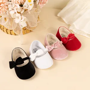 Detail view of four velvet baby princess shoes in black, white, pink and red with bow accents