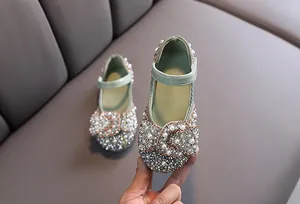 Close-up detail of sparkly green girls dress shoes with rhinestone and pearl bow design