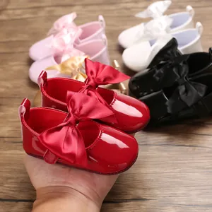 Primer plano de zapatos rojos de princesa para bebé con un gran lazo de satén