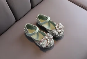 Detailed view of girls' sage green Mary Janes with rhinestone and pearl bow