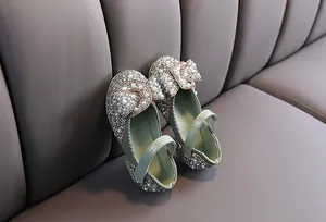 Detailed view of sparkling rhinestones and pearls on light green girls bow performance shoes