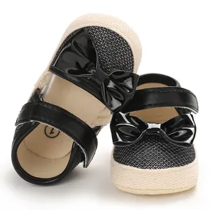 Close-up of black baby girl Mary Jane shoes with patent leather bows and textured mesh.