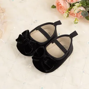 Close-up of black velvet baby princess shoes with elegant bow details and soft soles