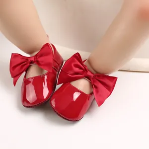 Primer plano de zapatos de bebé en charol rojo con grandes lazos de satén elegantes