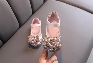 Detail shot of girls pink dress shoes featuring sparkling rhinestones and pearl bow
