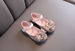 Elegant glittery pink girls' dress shoes featuring a large rhinestone bow and pearl accents