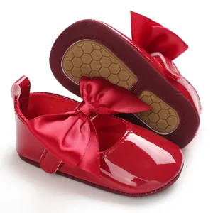Detalle de zapatos de princesa para bebé en charol rojo con lazo grande y suela