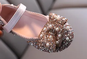 Close-up detail of girls' pink Mary Jane shoes with sparkling pearl and rhinestone bow