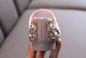 Macro detail of rhinestones and faux pearls on pink girl's performance dance shoe