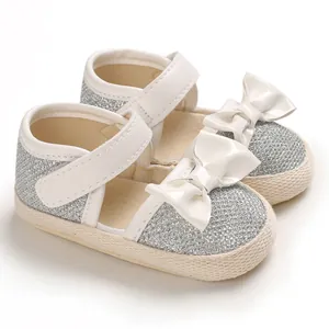 Detailed macro view of silver glitter baby princess shoes with white bows and soft soles
