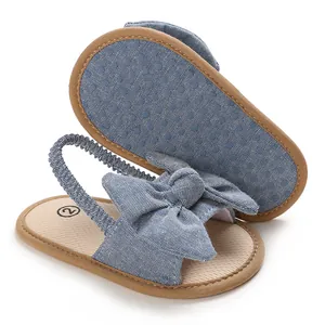 Primer plano de sandalias de bebé en denim azul con lazo y suela antideslizante