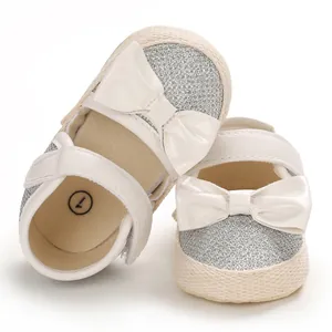 Detail of baby walking shoes with white bow and silver glitter finish for toddlers.