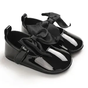 Detalle de zapatos de princesa para bebé en charol negro con un gran lazo de satén suave