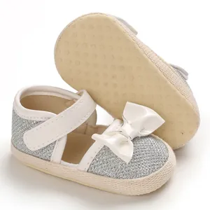 Detailed view of silver glitter baby princess walking shoes with a white bow decoration