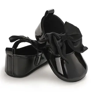 Primer plano de zapatos de charol negro para bebé niña con grandes lazos decorativos