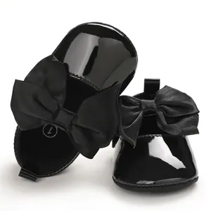 Primer plano de los zapatos de charol negro para bebé con elegantes lazos grandes