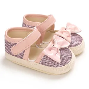 Close-up detail of pink glittery baby walking shoes with cute bow and soft woven sole