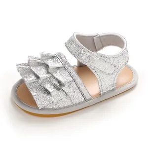 Nahaufnahme von silbernen Glitzer-Babysandalen mit niedlichen Rüschendetails und Klettverschluss