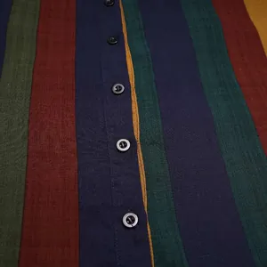 Detailaufnahme eines vertikal mehrfarbig gestreiften Herrenmantels mit schwarzem Knopfverschluss
