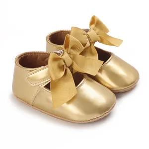 Detaillierte Nahaufnahme von glänzenden goldenen Baby-Prinzessinnen-Schuhen mit großen Schleifen