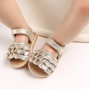 Nahaufnahme von goldenen glitzernden Babysandalen mit Rüschendetails an Babyfüßen