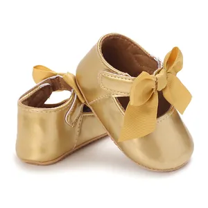 Nahaufnahme goldener Baby-Lauflernschuhe mit feiner Schleife und weicher Gummisohle