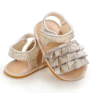Nahaufnahme von goldenen Glitzer-Babysandalen mit elegantem Rüschendesign vorne