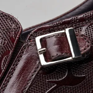 Close-up detail of crocodile embossed leather and silver buckle on men's shoe.