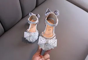Detail view of sparkly silver girl's princess shoes with large rhinestone bow