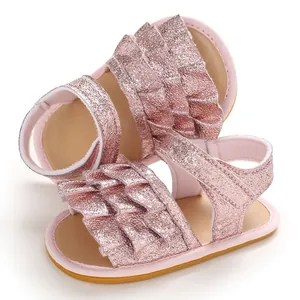 Nahaufnahme von rosa glitzernden Babysandalen mit Rüschenriemen und rutschfesten Sohlen