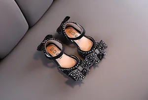 Detailed view of elegant black girls' princess shoes featuring rhinestones and bows