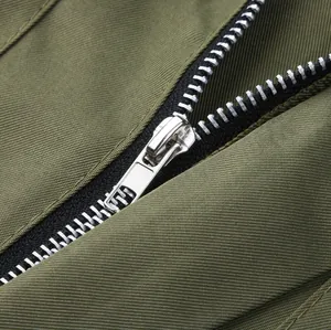 Detailed macro view of durable silver metal zipper on olive green men's workwear jumpsuit.