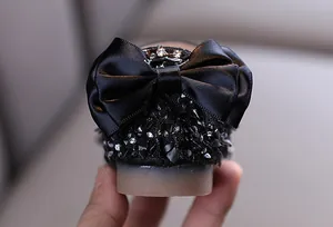 Detailed view of black satin bow and sparkling beaded heel on girl's princess dress shoes