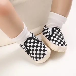 Soft sole baby walking shoes with classic black and white checkerboard pattern on feet